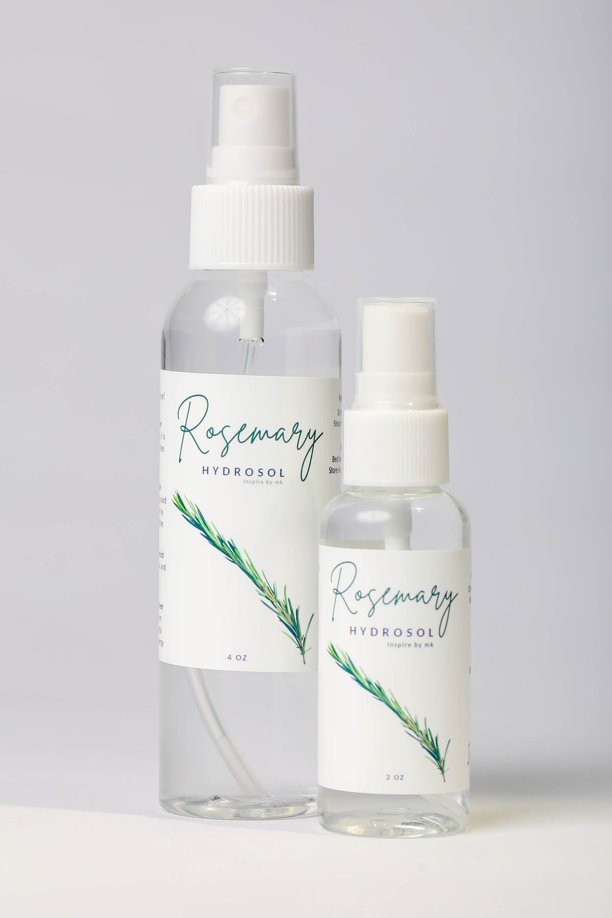 Rosemary Hydrosol spray bottles in 4oz and 2oz sizes with fresh rosemary branches. All natural organic rosemary hydrosol facial mist, stimulating body spray, and natural face toner made with pure steam-distilled rosemary.