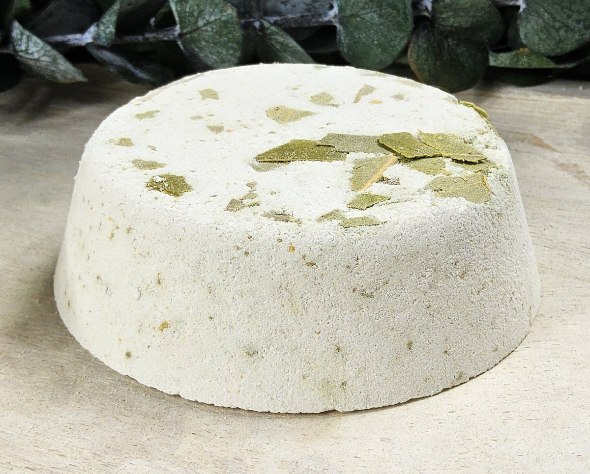 InspireByMK Eucalyptus shower steamer handcrafted dome with cream base and green dried eucalyptus leaves, surrounded by fresh eucalyptus stems showing pure eucalyptus essential oil with eucalyptus hydrosol for respiratory wellness and invigoration