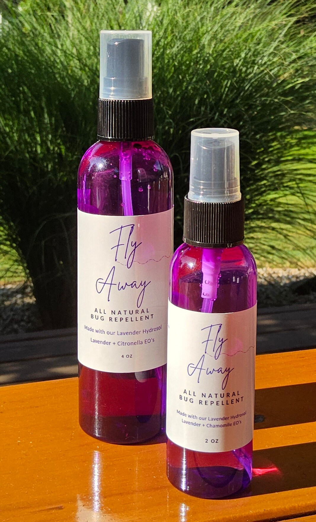 InspireByMK Fly Away Lavender All Natural Bug Repellent duo featuring 4 oz and 2 oz purple glass spray bottles with black caps, made with lavender hydrosol, lavender and citronella essential oils, DEET-free kid and pet-safe insect repellent displayed with fresh lavender foliage
