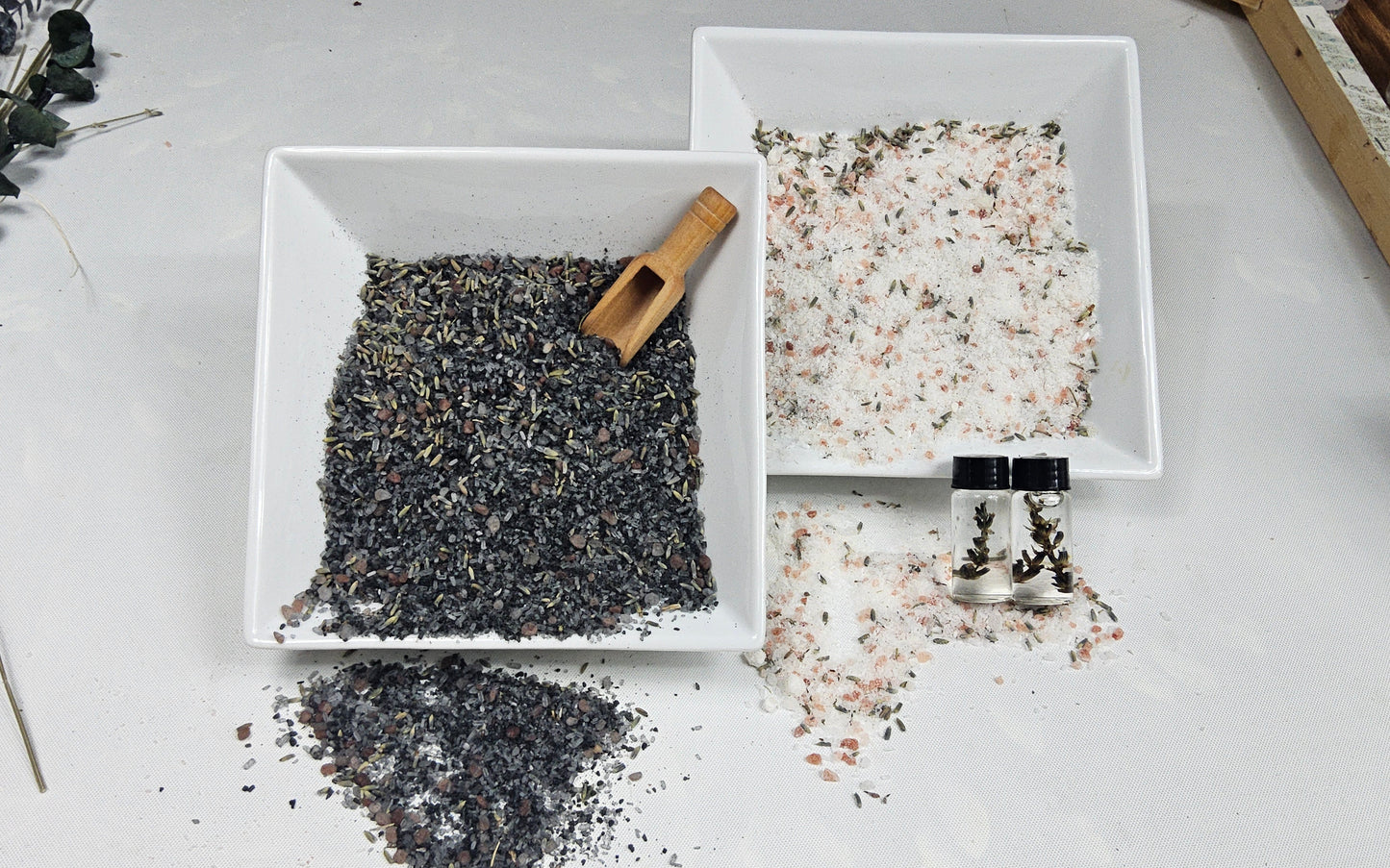 InspireByMK Lavender bath salts product display showing dark lava blend and light epsom blend with dried lavender buds in white ceramic bowls, wooden scoop, and complementary lavender hydrosol bottles for natural aromatherapy spa soaks