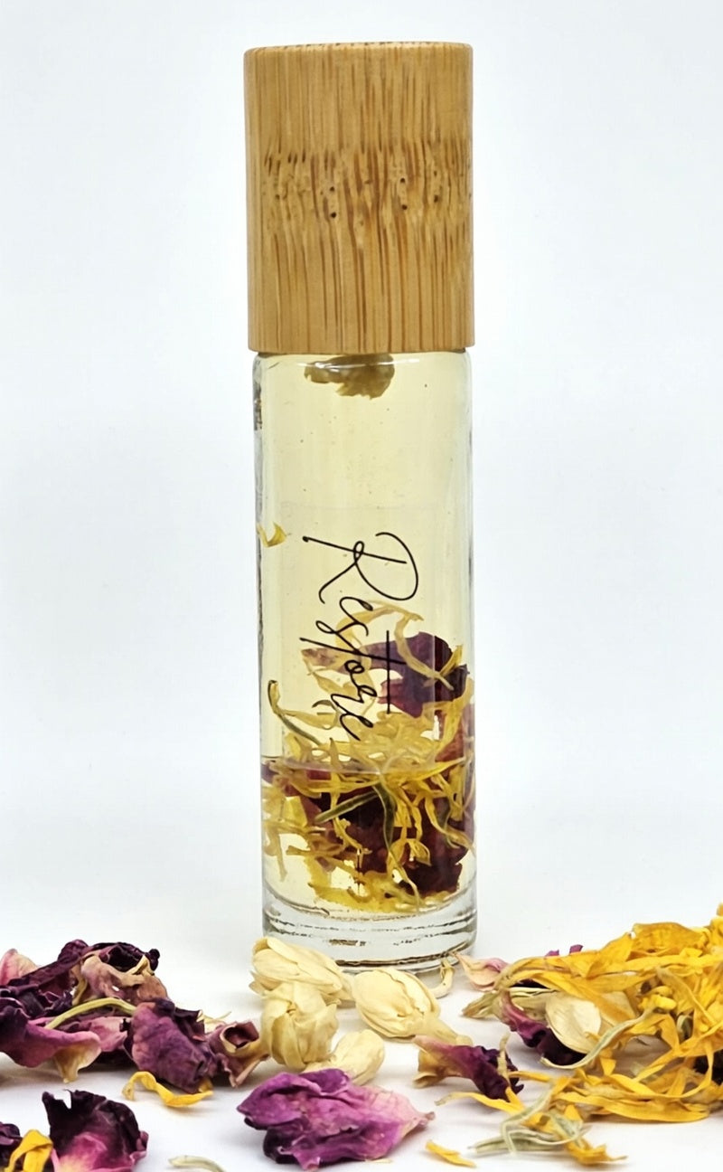 Restore essential oil roller bottle with real dried rose petals, jasmine, and calendula flowers inside. Calming all-natural aromatherapy roller made with bergamot, patchouli, and sandalwood essential oils in a base of vitamin E and sweet almond oil for grounding and emotional balance.